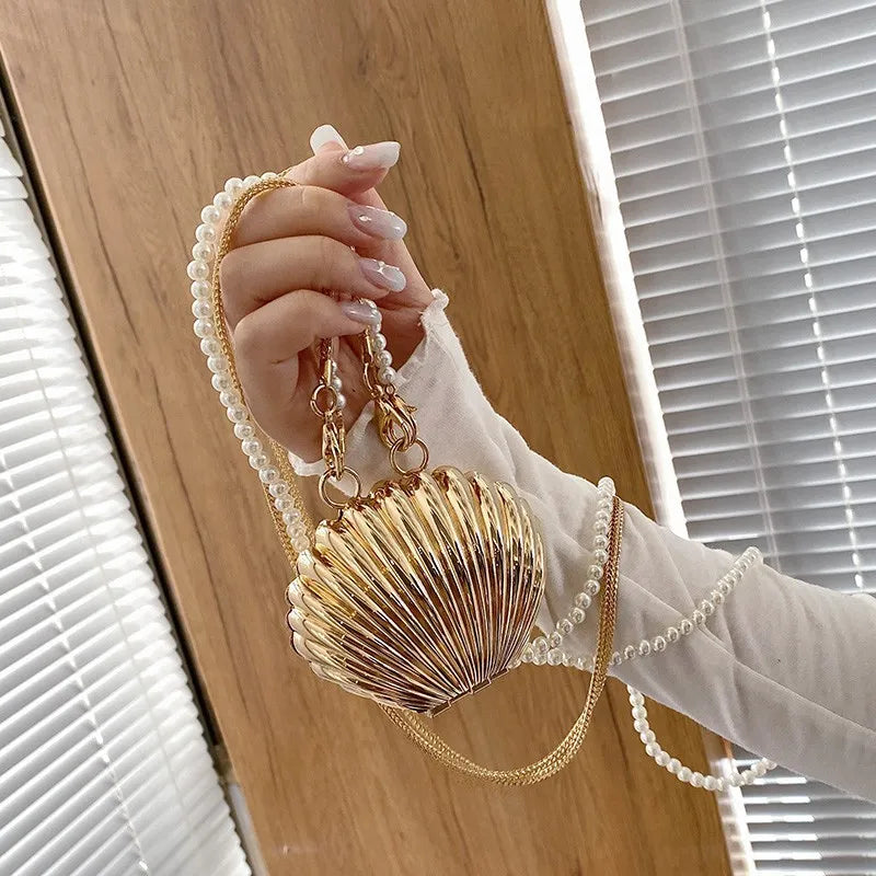 Bolso Dorado o Plateado Metálico con Forma de Concha y Cadena de Perlas.